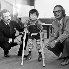 Stefan as a young boy in braces and on crutches, between two men