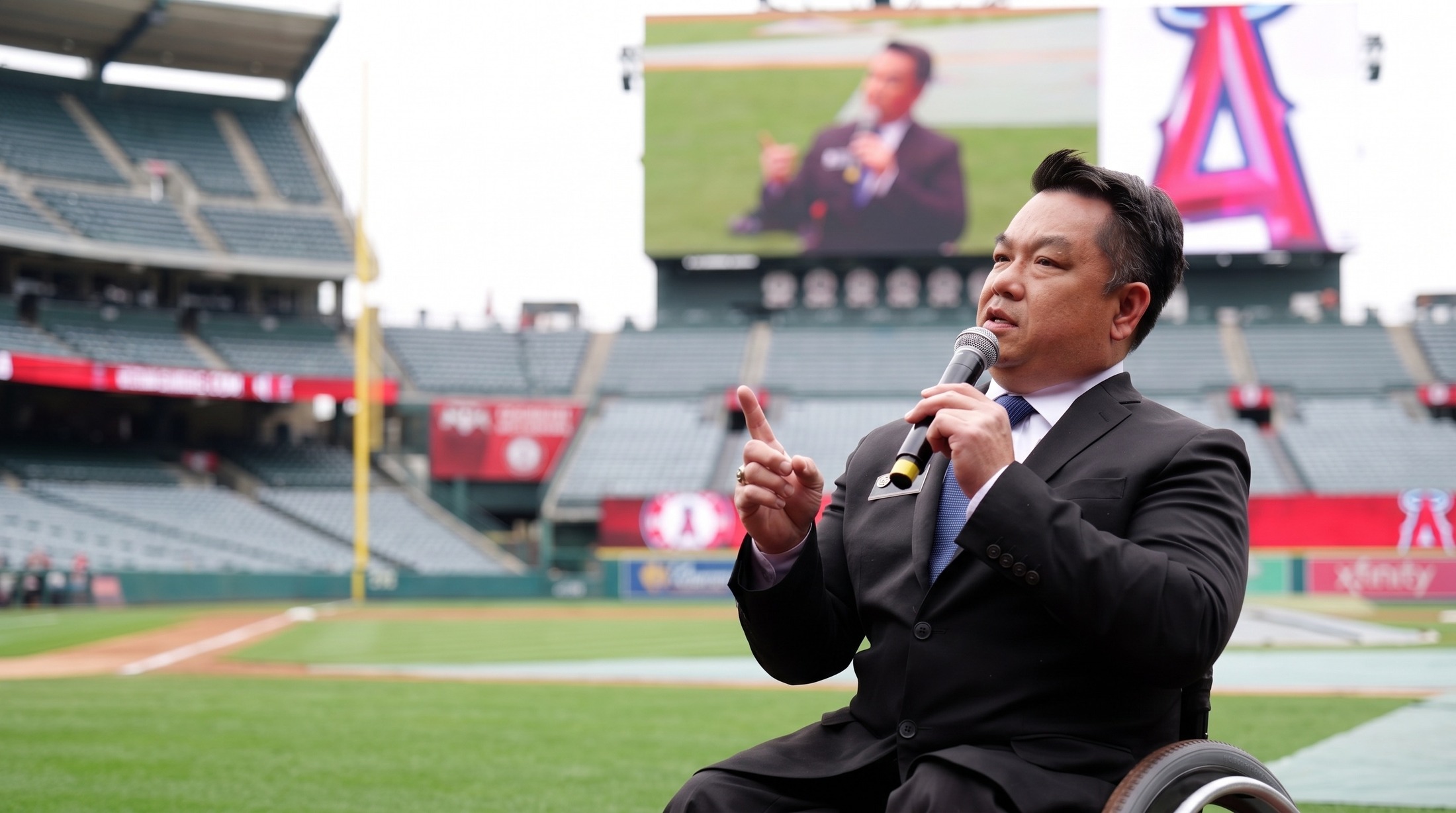 Dr. Bean speaking with a microphone on the field at Angel Stadium